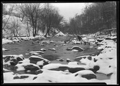 A view of snow-covered rocks in the Gwynns Falls, a 24.9 mile-long stream located in the southwestern part of Baltimore County and Baltimore City, Maryland. The stream begins in Reisterstown, Maryland, and flows southeast into Baltimore City, where it empties into the Middle Branch of the Patapsco River. Named for Richard Gwinn, who opened a…