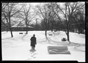 View of a winter scene in Druid Hill Park, Baltimore, Maryland. The image features a gazebo, benches, and a man walking through the snow.