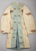 Child's fancy dress coat made from earlier floral fabric and trimmed with wide bands of blue silk satin. Embellished with metallic buttons on front and around vent in back. Lined with cotton flannel.