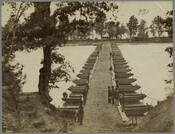 View of a pontoon bridge on Deep Bottom, an area of the James River in Virginia. More than a dozen Union soldiers from the American Civil War are visible in the foreground.