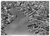 Aerial view looking northwest at the Inner Harbor and downtown Baltimore, Maryland. At center are the Pratt Street wharves and to the upper left are the Light Street wharves. Visible at lower left are Bethleham Shipbuilding's Key Highway yards and to the right are the tracks, trainsheds, and warehouses of the Pennsylvania Railroad's President Street…