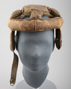 Early padded leather football helmet comprised of a leather ring with four square padded flaps attaching to a central pad at the crown of the head. Ear covers of padded leather are attached underneath the ring with a strap on right ear cover to latch under the chin to the other ear. Robert E. Lee…