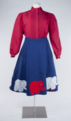Ensemble comprised of a red blouse (2015.20.9) with full-length sleeves, high collar, and pin-tuck detail, and a blue, mid-length elephant campaign skirt (2015.20.8). Worn by former Maryland State Representative, Helen Delich Bentley when campaigning for her position in the mid 1980s.