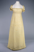 White cotton dress with horizontal yellow silk stripes. Dress has empire waist and cap sleeves. Likely worn by Mrs. Samuel Gilpin (b.1803).