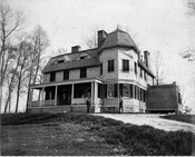 View of the main house on the Kedleston estate, located in Ruxton, Maryland. Two men stand in front of the building. Designed by John Appleton Wilson and his cousin William Thomas Wilson, this 18-acre estate was the country seat of Richard Curzon Hoffman (1839-1926), a Baltimore stock broker and railroad official.