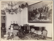 The parlor room of the original Guilford mansion. Visible in the photograph are chairs, tables, ewers, a large framed painting, a chandelier, and a piano. William McDonald inherited the Guildford estate from his father, General McDonald, in 1850, and built the Guilford mansion upon the land. John De Speyer became the next owner, and then…