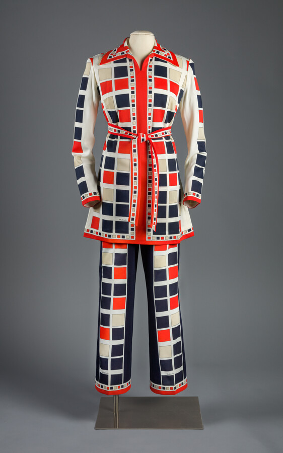 A red, white, and blue block-print polyester knit pantsuit, designed by Mr. Dino. Max Cohen, known professionally as Mr. Dino, designed every print for his garments and proudly signed each piece of an ensemble. His signature appears once on the trousers and twice on the tunic.