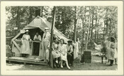 A view of a group of people standing in front of a tent with ice cream for sale at Camp Hutzler. Established by Albert and Joel Hutzler, of the Baltimore-based Hutzler's department store, the camp ran from 1921 to 1923. From July through September, employees of Hutzler's could go to the camp, located in the…