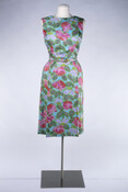 Lady's sleeveless mid-length cocktail dress with a high neck in a polychrome floral print with matching belt. Bought at a Hutzler's department store and worn by the donor.