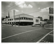 A view of the exterior of the Greyhound bus terminal located at 601 North Howard Street in Baltimore, Maryland. Designed by architect William S. Arrasmith (1898-1965) in the Streamline Moderne style, the building featured elements characteristic of the style such as a tall pylons, long horizontal lines, and a flat roof. The terminal was in…