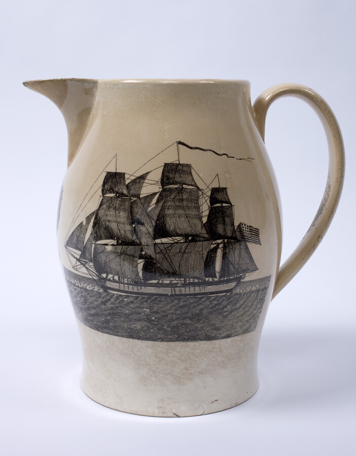 Creamware pitcher manufactured by Herculaneum Pottery in Liverpool, England. On one side is a black transfer print of a ship flying the American flag. On the opposite side, the motto "PEACE, PLENTY AND INDEPENDENCE" is displayed in an oval medallion that is flanked by female figures holding cornucopias, a cannon, battle flag, and spread-wing eagle.…