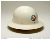 White metal helmet worn by an air raid warden during World War II. Marked with the numbers "4-1-9" and an emblem featuring a red and white striped triangle inside a blue circle.