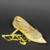Yellow kid leather ladies' slipper with tie and small Italian Louis heel. Embellished with a pom-pom at the pointed toe.