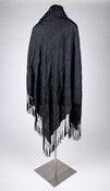 Black silk shawl embellished with black floral embroidery throughout and with a rolled fringe on all four sides.