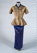 Two-piece ensemble worn by the Duchess of Windsor, Wallis Simpson (1896-1986). Consists of a silk brocade peplum-waisted short-sleeved blouse. The fabric is designed with a blue, red and white butterfly pattern on a gold field, and with a blue lining and collar. The blouse closes in front with a row of 15 small covered buttons.…