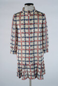 Shift dress with large red, white, and blue tartan pattern. Dress buttons up in the front and has full-length sleeves, a funnel neck, and a ruffled hem. Worn by the Duchess of Windsor, Wallis Simpson (1896-1986).