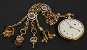 Gold pocket watch, bordered with pearls, featuring a long jeweled train with blue enamelwork. The reverse side features a color illustration of two women and two children on a translucent cobalt background. This ornate watch would have only been available to the wealthiest individuals in the late-18th century. This one belonged to Charles Carroll of…