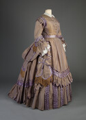 Shot silk taffeta carriage or visiting dress worn by Anne “Annie” Campbell Gordon Thomas (1819–1886).The bodice comprises changeable lavender & gold silk taffeta with lavender satin trim, separate collar, cuffs attached, and bust with large pads. Also features an under skirt of same with silk fringe trim, bustle overskirt of same, and matching belt with…