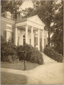 Exterior of the Homewood estate with an unidentified adult and child standing on the front porch. Homewood was built between 1801 and 1806 as a country home for Charles Carroll, Jr, son of Charles Carroll of Carrollton who was a signer of the Declaration of Independence. The Federal-period Palladian home was in the Carroll family…