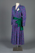 A two-piece purple, pink, and green swirl patterned polyester dress that comprises of a skirt, blazer, lace handkerchief, and green dupioni silk sash.