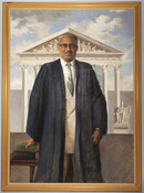 Three-quarter length portrait of former Associate Justice of the Supreme Court of the United States, Thurgood Marshall (1980-1993). He is portrayed with short gray hair, dark rimmed glasses, and a mustache. He wears his justice robes over a tan suit with a striped green tie. He is pictured standing outside of a courthouse underneath a…