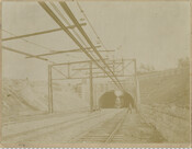 A southbound Baltimore & Ohio Railroad train emerging from a Baltimore Belt Line tunnel, possibly on the west side of Huntington Avenue in North Baltimore, Maryland. Overhead conductor rails and electrical cables are also visible. The Baltimore Belt Line was constructed by the B&O in the early 1890s in order to connect its newly constructed…