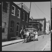 An arabber, or horse-cart vendor, selling fresh produce on Durham Street in East Baltimore, Maryland. The term “arabber” is unique to Baltimore and these sellers have operated in the city since the early 19th century. Recognized as a primarily African American folk tradition by the Arabber Preservation Society, arabbers continue to serve a practical purpose…