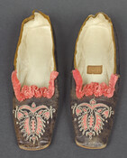 Pair of women's black leather shoes with pink silk ruched trim. The leather at the shoes' tops feature floral motif cut-outs that reveal pink silk underneath. Chain stitching decorates the edges of the leather cutouts. A label inside one shoe reads "D. ARDIN, / No. 4 / South Street / 3 doors from Market/ Baltimore".…