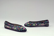 Black Chinese slippers with multicolored floral embroidery throughout. Slippers have narrow rounded toe, curved sole, and one-layer stacked heels.