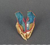 Small Chinese embroidered slipper for girl with bound feet. Exterior of slipper is off-white with floral embroidery. Interior is lined with blue fabric and edges are bound with purple silk. Brought from China by William Steel Forrest of the United States Navy.