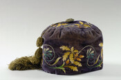 Purple velvet smoking cap embellished throughout with floral embroidery and green tassel extending from top center. Lined with white quilted silk.