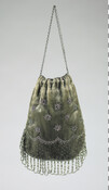 Green-gray silk velveteen purse with embroidered steel cut bead design of starbursts with scalloped lower border. Interlocking loop beaded fringe at bottom edge. Drawstring casing contains two chain handles. Lined with grey silk satin.