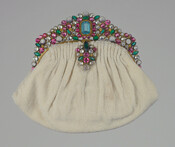 Beaded ivory clutch evening bag with pink, crystal, and green jeweled gold metal filigree handle. Exterior gathered and attached to gold metal hinged frame with snap clasp. Matching jeweled pendants suspended at front. Lined with ivory satin featuring an assortment of vertical and horizontal self-pockets.