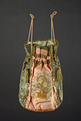 Peach and mint green silk handbag with metallic lace trim features multi-colored hand-embroidered basket of flowers on front while the back was left plain. Oval-shaped bottom of bag covered with peach silk. Sides of bag are mint green silk covered with brown silk and gold metallic lace. Casing decorated with metallic lace forms top of…