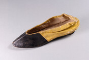 Child's yellow and black painted kid leather shoe with pointed toe and small heel. Shoe has linen lining, black toe box, yellow from mid-foot to heel.