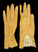 Pair of gold-colored kid leather ladies' gloves. Closes with two mother-of-pearl buttons at each scalloped cuff.