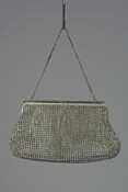 Purse made of synthetic rhinestones stitched together over a white satin lining, containing pocket with matching covered mirror. Handle of white metal links forming a chain. Worn and owned by Elizabeth Hill Hartley Rose (1906-1987), who attended Roland Park Country School and traveled extensively across Italy and France.