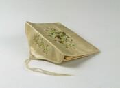 Ivory silk satin card case with floral spray designs embroidered in silk thread. Remnants of a silk ribbon tie closure remain. Case has gusseted sides and an interior divider.