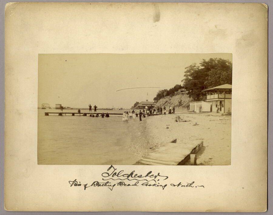 Approximately 25 figures wading annd standing on a pier at the bathing beach in Tolchester, Maryland. Tolchester was the site of the Tolchester Beach Amusement Park, which consisted of a bathing beach, amusement park, racetrack, and hotel, and was in operation from 1877 to 1962. The Kent County park was a popular vacation destination for…