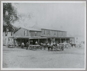 Approximately 15 figures standing amidst horses and wagons in front of an inn and general store located in Head of Sassafras, Maryland. John Fagan Ernest, seen with his hand on the wheel of a wagon, owned the property and ran the general store from 1869 to 1915. The building was destroyed by a fire in…
