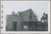 Exterior view of a general store in Chesterville, Maryland, run by Mary Messick. The porch is filled with items and a sign hangs from the side of the building. Before serving as a store, the building was an inn known as the Chesterville Hotel.