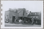 Exterior view of a general store run by Mary Messick in Chesterville, Maryland. A figure, possibly Messick, stands in front of the building. Before serving as a store, the building was an inn known as the Chesterville Hotel.