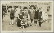 Group portrait of ten swimmers in bathing suits and caps posing on the sand at Betterton Beach in Kent County, Maryland. Located at the end of a peninsula where the Sassafras River enters the Chesapeake Bay, Betterton was a popular beach resort on the Eastern Shore during the late 19th and early 20th centuries.