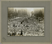 A large crowd gathered at Mount Vernon Place in Baltimore, Maryland, to celebrate the arrival of the Marshal of France, Joseph Jacques Césaire Joffre, and the French Mission. Many of the figures wave small American flags and several members of the crowd hold banners. The Enoch Pratt house can be seen in the background. Joffre…