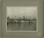 View of the "Louise," a sidewheel passenger steamship, owned by the Tolchester Steamboat Company. The decks of the ship are filled with passengers. The "Louise" was one of the most popular excursion steamers on the Chesapeake Bay and could hold 2,500 people. The company ran daily excursion steamships from its pier at Light Street in…