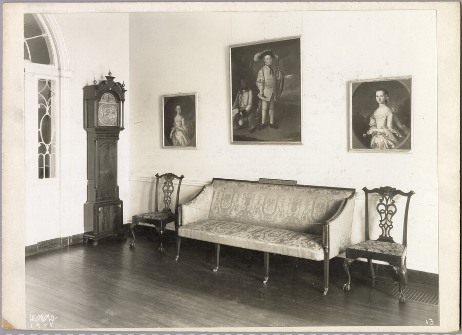 View of an entryway in the Homewood estate, including a sofa, chairs, grandfather clock, and three framed portraits. Homewood was built between 1801 and 1806 as a country home for Charles Carroll, Jr., son of Charles Carroll of Carrollton who was a signer of the Declaration of Independence. The Federal-period Palladian home was in the…