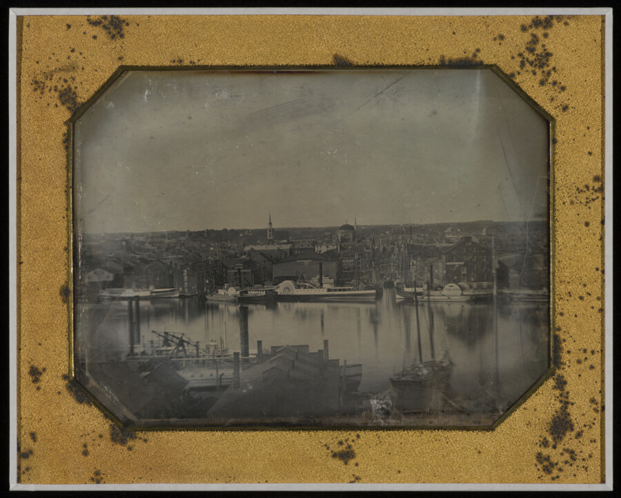 View of Gay Street dock in the harbor of Baltimore, Maryland, looking northeast from Federal Hill. The image shows the ships Herald and Juniata. This full-plate daguerreotype is part of a series of photographs considered to be the first comprehensive photographic recording of Baltimore City.
