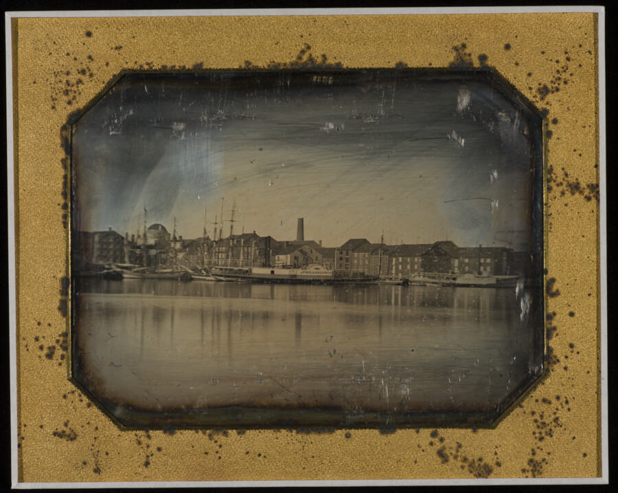View of the harbor in Baltimore, Maryland, looking north east from Federal Hill. Phoenix Shot Tower, the ship Constitution, and Coffee Row are visible. This full-plate daguerreotype is part of a series of photographs considered to be the first comprehensive photographic recording of Baltimore City.