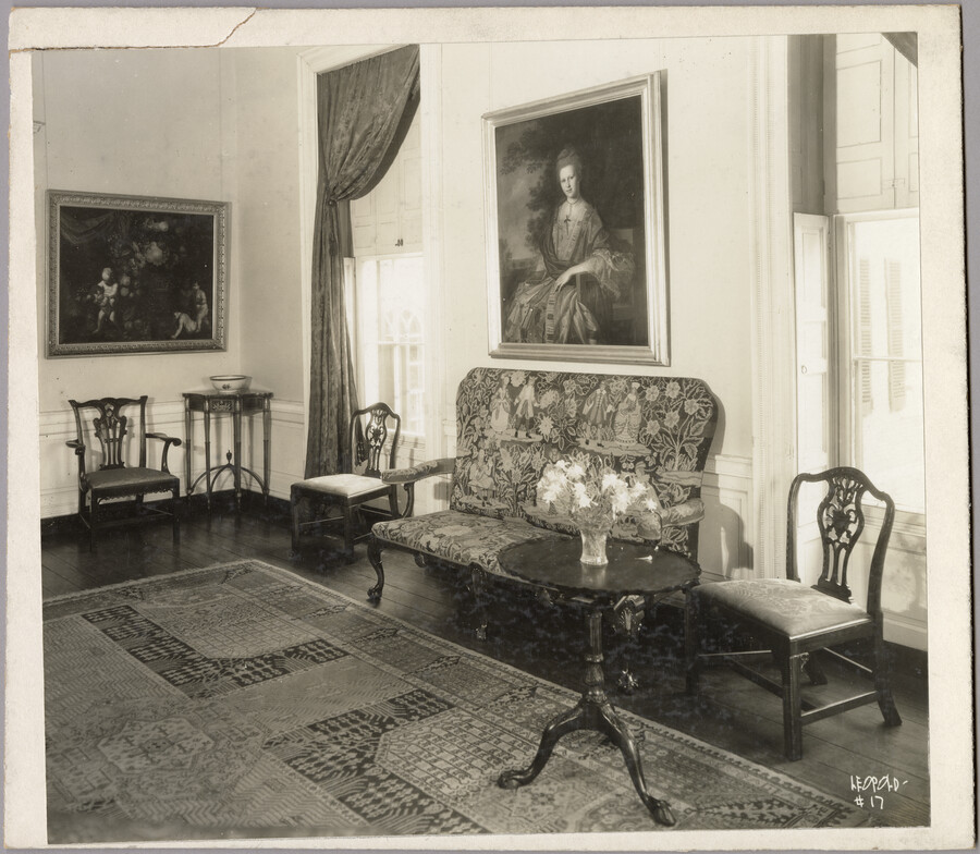 View of a seating area in the Homewood estate, with a sofa, rug, chairs, tables, and two framed portraits. Homewood was built between 1801 and 1806 as a country home for Charles Carroll, Jr., son of Charles Carroll of Carrollton who was a signer of the Declaration of Independence. The Federal-period Palladian home was in…