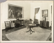 View of a seating area in the Homewood estate, with various pieces of furniture and decor, two framed paintings, and a large rug. Homewood was built between 1801 and 1806 as a country home for Charles Carroll, Jr., son of Charles Carroll of Carrollton who was a signer of the Declaration of Independence. The Federal-period…